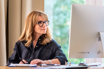 Attractive businesswoman sitting at home and using computer for work