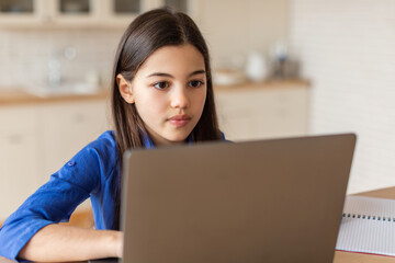 Smart arab girl schooler sitting at modern laptop from home