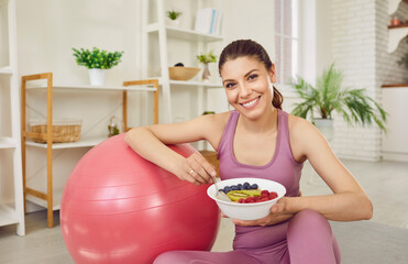 Portrait of a young sporty slim woman wearing sportswear eating healthy food after working out at...