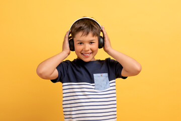Happy child school aged boy listening to music, using headphones