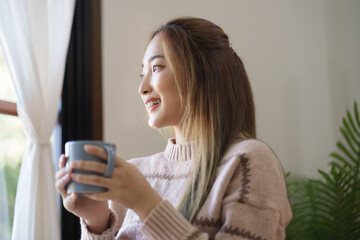 Asian girl drinking coffee at home in the morning.