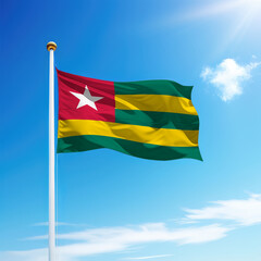 Waving flag of Togo on flagpole with sky background.