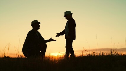 Dad plays with his little child, teaches his son how to shake hands, hello dad. Father and beloved child have fun together. Happy family concept. Boy, dad shake hands in park at sunset. Walk outdoors