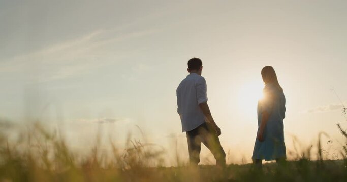 A married couple stands at sunset and looks ahead. Relationships and family concept