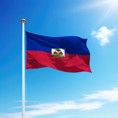 Waving flag of Haiti on flagpole with sky background.