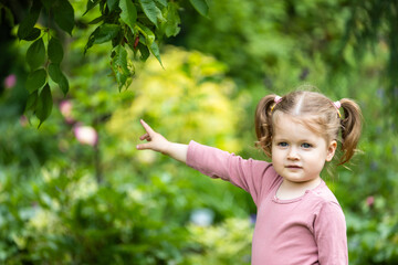 toddler girl is interested in outdoor nature - obrazy, fototapety, plakaty