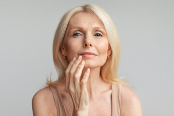 Portrait of mature woman touching lips with finger, beautiful aged lady enjoying self-care routine,...