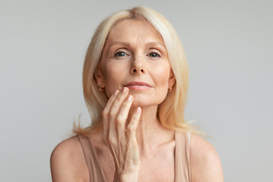 Portrait of mature woman touching lips with finger, beautiful aged lady enjoying self-care routine, closeup