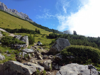 A picturesque view of stone boulders scattered on the rocky mountain slopes of the rocks against the background of the blue sky