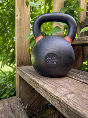 Fototapeta na wymiar heavy iron competition kettlebell for weight training on wooden rustic stairs in backyard, home gym and fitness concept