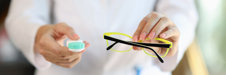 Woman doctor holding glasses and contact lens case