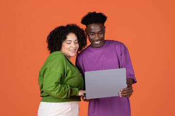 Happy interracial couple shopping online, using laptop