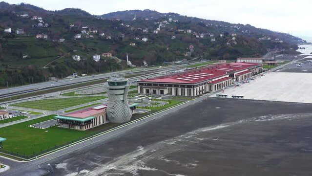 4K drone footage of Rize-Artvin Airport in daylight. Aerial shooting of green village on grassy slopes overlooking Black Sea, airport and motor way. The tarmac and runway stock video.