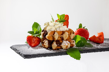 Belgian waffles with strawberries on slate board white background
