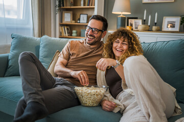 Couple caucasian man and woman sit at home on sofa bed watch tv movie - Powered by Adobe
