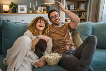 Couple caucasian man and woman sit at home on sofa bed watch tv movie - Powered by Adobe