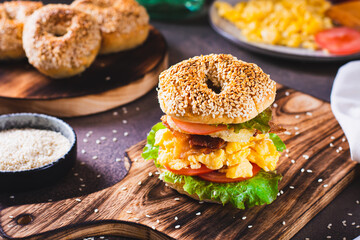 Hearty bagel burger with scramble egg, bacon, cheese, tomato and lettuce