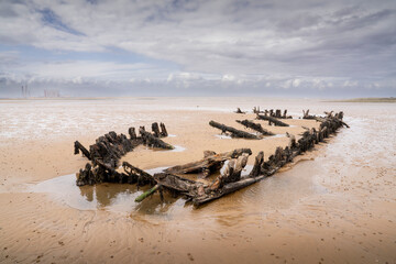 Wooden boat skeleton in the sand at low tide