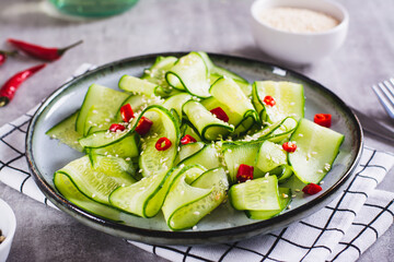 Spicy salad of cucumber slices, hot red pepper and sesame seeds on a plate