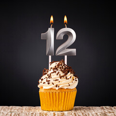 Birthday candle number 12 - Anniversary cupcake on black background