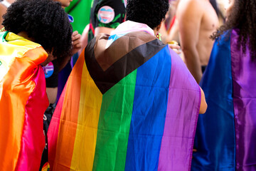Jovens na 27ª Parada do Orgulho LGBT+ vestidos com a bandeira símbolo do orgulho gay. Avenida Paulista, São Paulo, Brasil.  - obrazy, fototapety, plakaty
