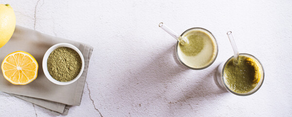 Iced matcha lemonade with lemon in glasses with straws on the table top view web banner