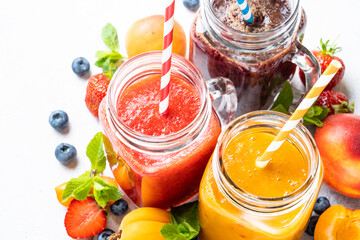 Smoothie with fresh fruits and berries at white background. Smoothie set in jars. Close up image.