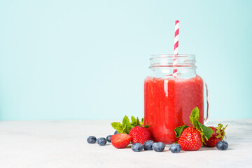 Strawberry smoothie with fresh berries at blue background.
