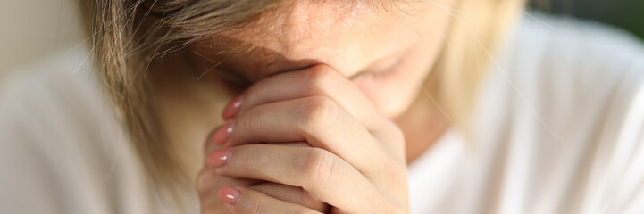 Young woman folded hands and praying at home alone
