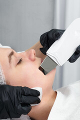 Ultrasound facial peeling. Brunette woman getting ultrasonic peel skin with skin scrubber at...