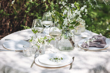 Rustic elegant eco friendly zero waste trendy wedding reception table decor with fresh spring apple cherry flowers in bloom. Beautiful marriage decoration, holiday event outdoors in the family garden