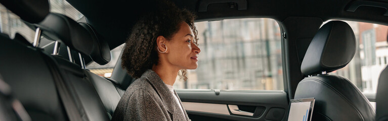 Executive woman sales manager working on laptop sitting car leather backseat on way to office