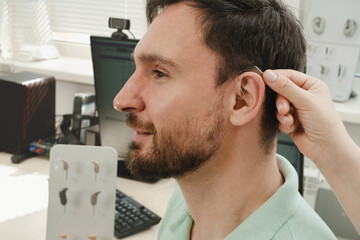 Man trying modern compact hearing aids. Closeup of patient ear. Hearing rehabilitation clinic...