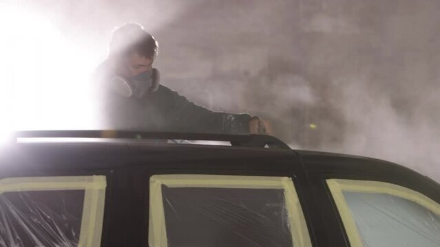 Protective gear, Protection gear, Protective masks. Man wearing respirator skillfully using spray gun to paint vehicle.