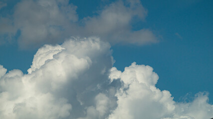 Naklejka na ściany i meble White fluffy cloud. Fluffy clouds at the blue sky. White cloud closeup