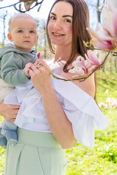 A woman holds her son near a blooming magnolia