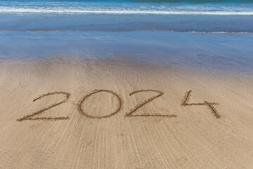 2024 written in the sand on the seashore with the arrival of the wave.