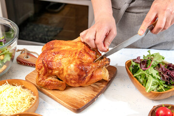 Woman cuts into a roast chicken for making Caesar salad.