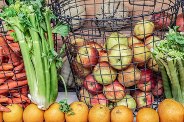 Fruits and vegetables in a metal wire basket at a grocery market. Organic biological products in a...