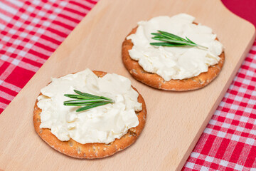 Crispy Cracker Sandwich with Cream Cheese and Rosemary on Wooden Cooking Board on Magenta Background