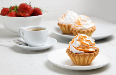 cakes cup of coffee and fresh strawberries in a plate on a light table. set . selective focus