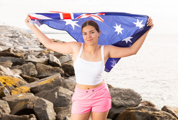Portrait of a positive girl with the flag of Australia on the seashore on a sunny day