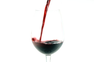close up of a glass goblet being filled with red wine , white background