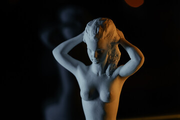 Naked woman's plaster sculpture, modern art. Art sculpture with yellow light on black background