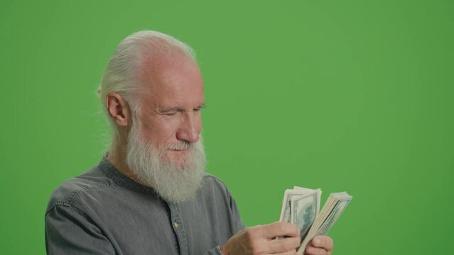 Green Screen.A Rich Old Man with a Gray Beard Counting His Money in US Dollars. An Elderly Man is Satisfied by the Amount of US Dollar Money in His Hands. Pension Provision.