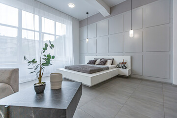 stylish bright modern bedroom interior with decorative niches with LED lighting and a huge panoramic window in gray and white colors and geometric shapes