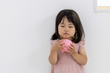 豚の貯金箱を持って落ち込んだ女の子（2歳11か月、日本人）