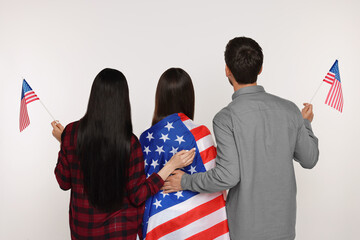 4th of July - Independence Day of USA. Family with American flags on white background, back view