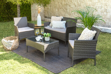 A modern outdoor rattan furniture living room set in a lush green grassy landscape - obrazy, fototapety, plakaty