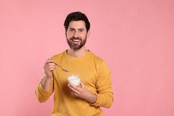 Handsome man with delicious yogurt and spoon on pink background. Space for text